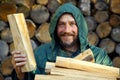 Portrait of a man with a bunch of chopped firewood. Bearded lumberjack with firewood for the fireplace.