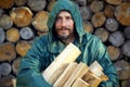 Portrait of a man with a bunch of chopped firewood. Bearded lumberjack with firewood for the fireplace.