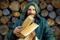 Portrait of a man with a bunch of chopped firewood. Bearded lumberjack with firewood for the fireplace.