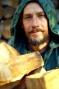 Portrait of a man with a bunch of chopped firewood. Bearded lumberjack with firewood for the fireplace. Royalty Free Stock Photo