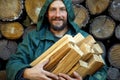 Portrait of a man with a bunch of chopped firewood. Bearded lumberjack with firewood for the fireplace. Royalty Free Stock Photo