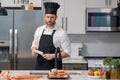 Portrait of man in chef apron and cook hat preparing fresh natural meal salmon at kitchen. Handsome cheerful chef man Royalty Free Stock Photo