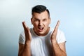 Portrait of a man close-up, experiencing anger, hate, against a light background. The concept of human emotions