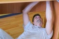 Portrait of man collecting parts of computer table screwing lying under table. Royalty Free Stock Photo