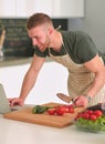 Portrait of man cooking vegetable in the kitchen while looking at a laptop computer on the table Royalty Free Stock Photo