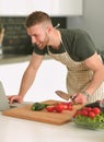 Portrait of man cooking vegetable in the kitchen while looking at a laptop computer on the table Royalty Free Stock Photo