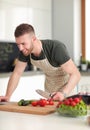 Portrait of man cooking vegetable in the kitchen while looking at a laptop computer on the table Royalty Free Stock Photo