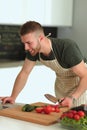 Portrait of man cooking vegetable in the kitchen while looking at a laptop computer on the table Royalty Free Stock Photo