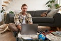 Portrait of man with dog, sitting on floor, has suitcase and laptop opened, booking or buying online, planning holiday Royalty Free Stock Photo