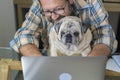 Portrait of man and dog working together at home with laptop computer - concept of free smart work lifestyle people - caucasian Royalty Free Stock Photo