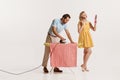 Portrait of man doing ironing while beautiful woman doing her makeup isolated over white background. Householder Royalty Free Stock Photo