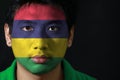 Portrait of a man with the flag of the Mauritius painted on his face on black background.