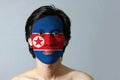 Portrait of a man with the flag of the North Korea painted on his face on black background.