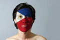 Portrait of a man with the flag of the Philippines painted on his face on black background.