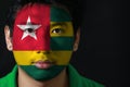 Portrait of a man with the flag of the Togo painted on his face on black background.