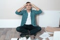 Portrait of a man on the floor holding his head, the difficulty of assembling furniture Royalty Free Stock Photo