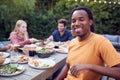 Portrait Of Man With Friends At Home Sitting At Table Enjoying Food At Summer Garden Party Royalty Free Stock Photo