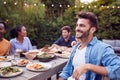 Portrait Of Man With Friends At Home Sitting At Table Enjoying Food At Summer Garden Party Royalty Free Stock Photo