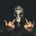 Portrait of man in gas mask, shows middle fingers sign by both hands