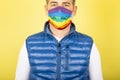 Portrait of a man with the gay pride symbol of the LGBTI social movement on yellow background