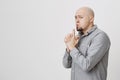 Portrait of man in gray casual shirt with gun hand gesture blowing at it looking confident isolated over white