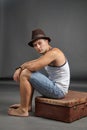 Portrait of a man in hat sitting on a suitcase Royalty Free Stock Photo