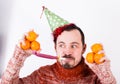 Male on holiday in hat and whistle with tangerines