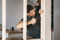 Portrait of a man in home clothes with a screwdriver in his hand fixes a wooden construction for a window in his house. Repair Royalty Free Stock Photo