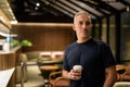 Portrait of man inside cafe restaurant at night holding coffee cup