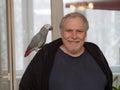 Man with a Jaco parrot on his shoulder