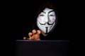 Portrait of man with laptop and vendetta mask isolated on black