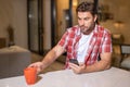 Portrait of man looking at smart phone at living room. Man is talking hold cup of coffe chatting on the smartphone