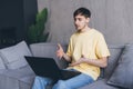 Portrait of man making video call on laptop sitting on couch at home, young mentor or trainer record online webinar or training, Royalty Free Stock Photo