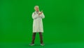 Portrait of man medic in studio on chroma key green screen. Senior doctor in white uniform draws injection in syringe