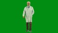 Portrait of man medic in studio on chroma key green screen. Senior doctor in white uniform walking looking at the camera Royalty Free Stock Photo