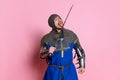 Portrait of man, medieval warrior or knight in armor with sword isolated over pink studio background Royalty Free Stock Photo