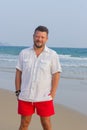 Portrait of a man with a middle beard in a white shirt and red shorts