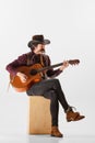 Portrait of man with moustaches in country cowboy style clothes playing guitar and harmonica, performing  over Royalty Free Stock Photo