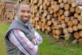 Portrait man next to stack felled trees