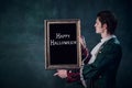 Portrait of man in noble medieval costume in image of vampire holding picture frame isolated over dark green background.