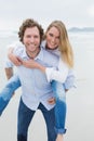 Portrait of a man piggybacking woman at beach Royalty Free Stock Photo