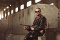 Portrait of a man from post-apocalyptic world with machine gun and the black glasses in an abandoned building