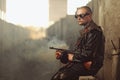 Portrait of a man from post-apocalyptic world with machine gun and the black glasses in an abandoned building