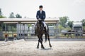 Man rider and black stallion eventing horse trotting leg-yield during equestrian dressage competition