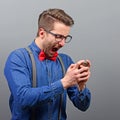 Portrait of man screaming on somebody while talking on cell phone against gray background Royalty Free Stock Photo