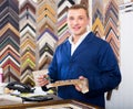 Portrait of man seller working with picture frames in atelier