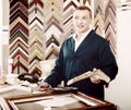 Portrait of man seller working with picture frames in atelier