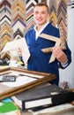 Portrait of man seller working with picture frames in atelier