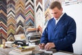 Portrait of man seller working with picture frames in atelier