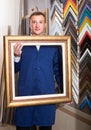 Portrait of man seller working with picture frames in atelier